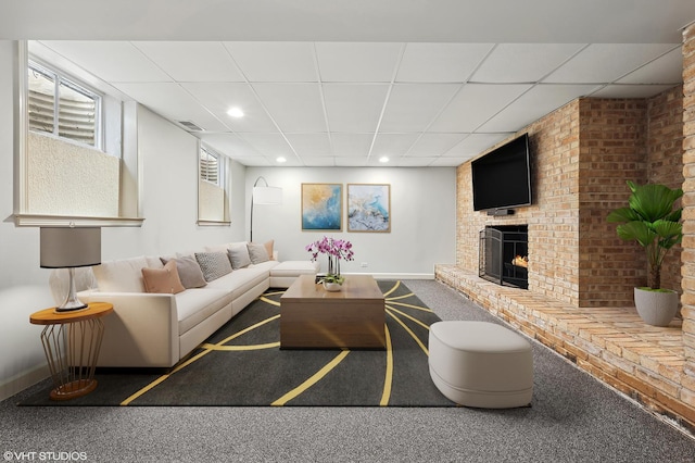 carpeted living room featuring visible vents, a brick fireplace, baseboards, a drop ceiling, and recessed lighting