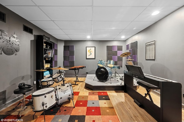 playroom featuring wood finished floors, a paneled ceiling, visible vents, and baseboards