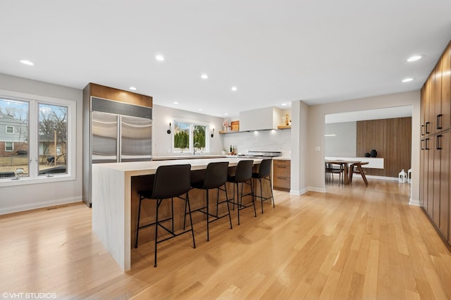 kitchen with a center island, a kitchen bar, light countertops, light wood-style floors, and open shelves