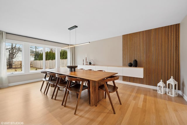 dining space featuring light wood-type flooring and baseboards