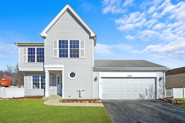 traditional-style house with aphalt driveway, a front lawn, a garage, and fence