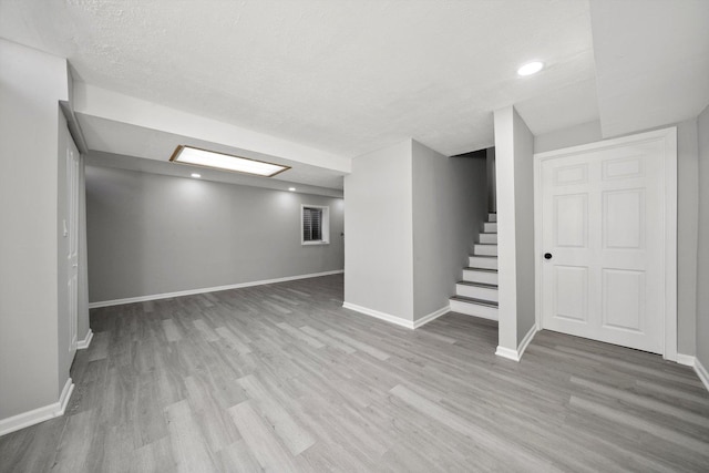 finished basement with stairs, baseboards, and wood finished floors