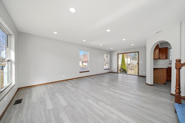 unfurnished living room featuring light wood-type flooring, visible vents, a wealth of natural light, and recessed lighting