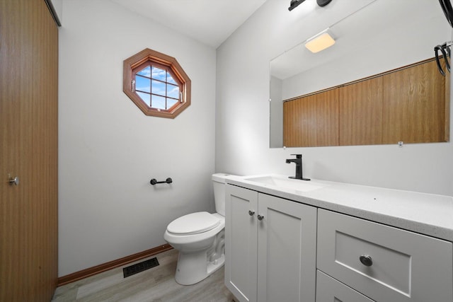 bathroom with vanity, wood finished floors, visible vents, baseboards, and toilet