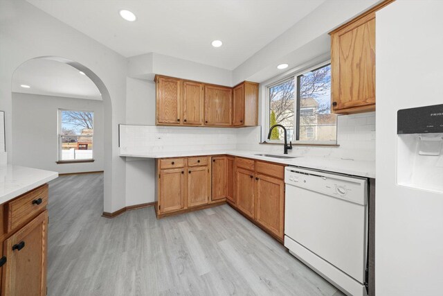 kitchen with a sink, white appliances, light wood-style floors, and light countertops