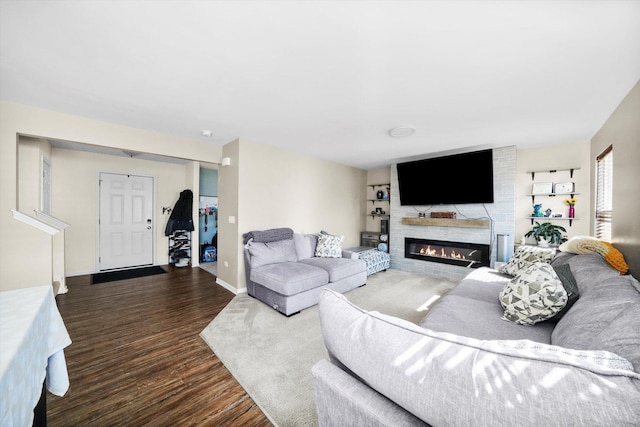 living room featuring baseboards, a large fireplace, and dark wood finished floors