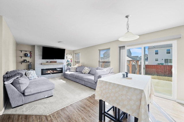 living area featuring baseboards, wood finished floors, and a glass covered fireplace