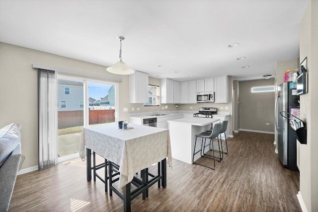 kitchen featuring white cabinets, dark wood-style flooring, appliances with stainless steel finishes, and a kitchen island