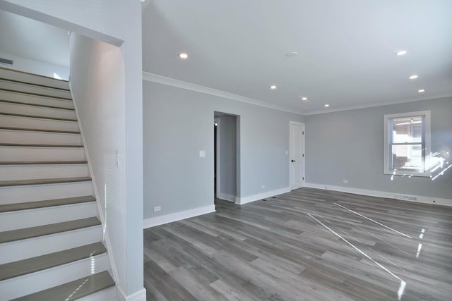 unfurnished room featuring wood finished floors, recessed lighting, stairway, crown molding, and baseboards