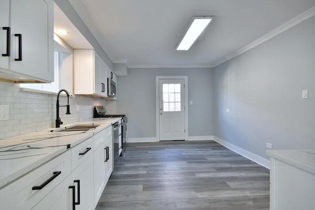 kitchen with backsplash, baseboards, ornamental molding, appliances with stainless steel finishes, and a sink