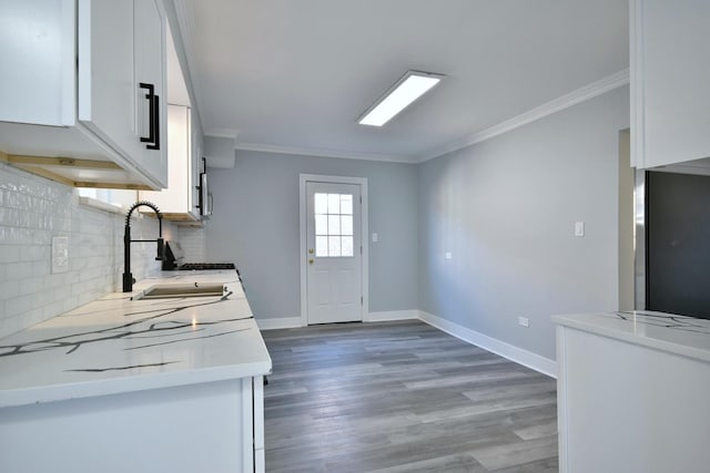 kitchen with a sink, baseboards, ornamental molding, and white cabinetry