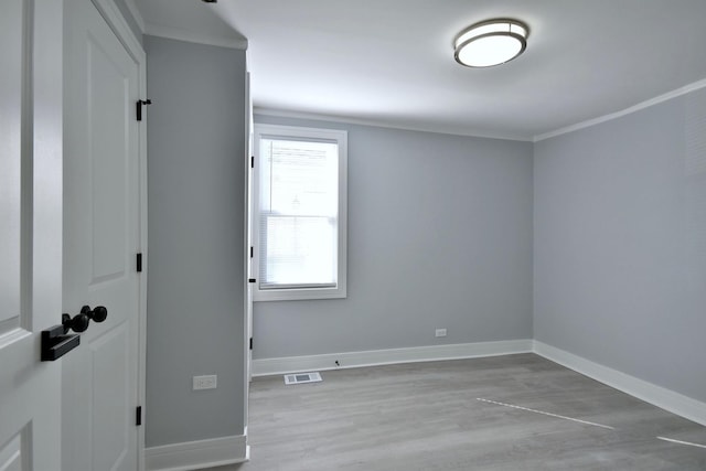 unfurnished room with visible vents, ornamental molding, baseboards, and wood finished floors