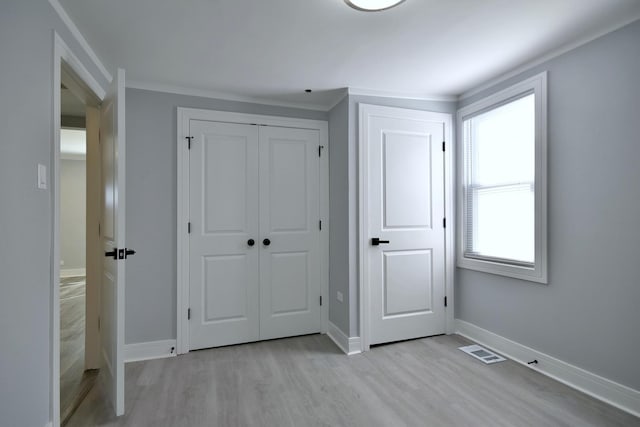 unfurnished bedroom featuring light wood-style flooring, baseboards, visible vents, and a closet