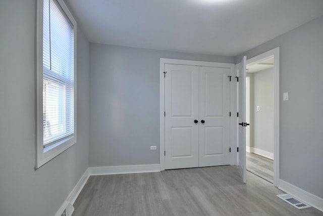 unfurnished bedroom with visible vents, baseboards, a closet, and light wood finished floors