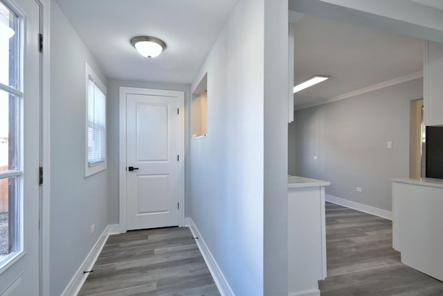 hallway with crown molding, baseboards, and wood finished floors