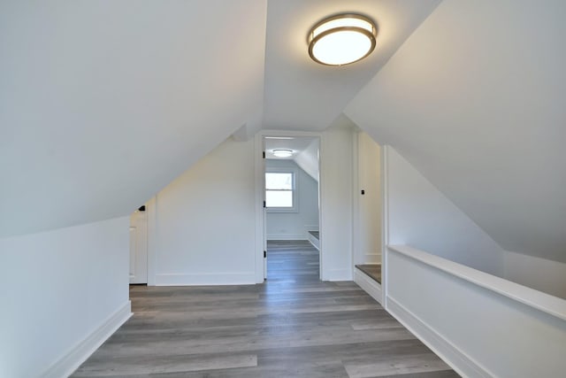 additional living space with vaulted ceiling, wood finished floors, and baseboards