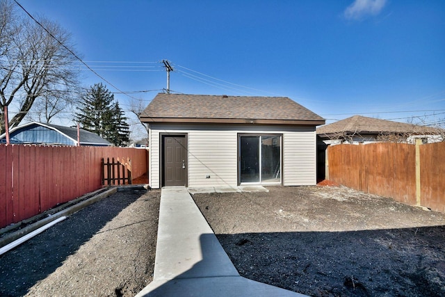 rear view of property featuring a shingled roof and a fenced backyard