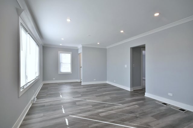 unfurnished room with visible vents, crown molding, baseboards, and wood finished floors