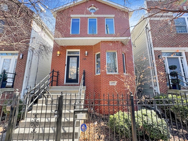 view of front of property featuring a fenced front yard, brick siding, and a gate