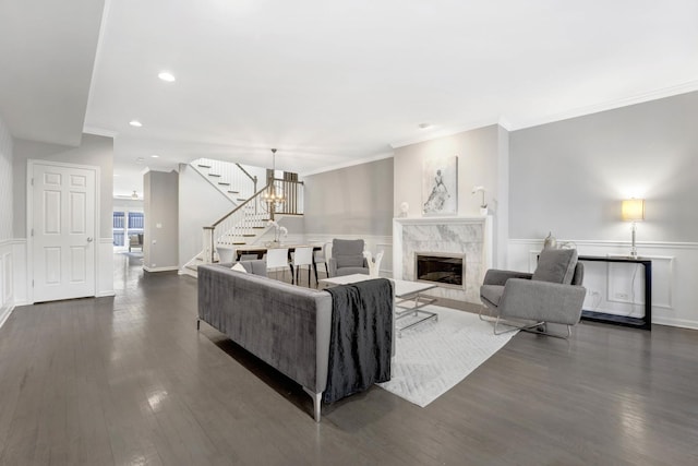 living area with stairway, wainscoting, a tile fireplace, and dark wood-type flooring