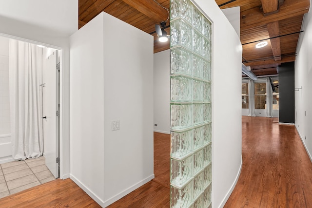 hallway with wood finished floors, wood ceiling, and beam ceiling