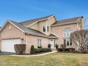 traditional-style house featuring aphalt driveway, a garage, and a front lawn