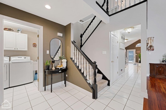 entrance foyer featuring light tile patterned floors, washer and dryer, stairs, and baseboards