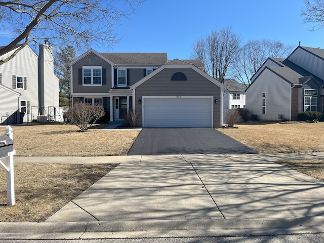 traditional-style home with an attached garage, fence, and driveway