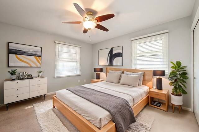 bedroom with a ceiling fan, light colored carpet, and baseboards