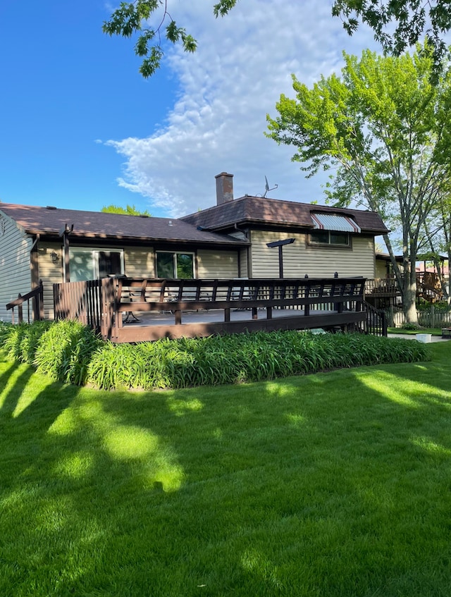 back of house featuring a yard, a deck, and a chimney