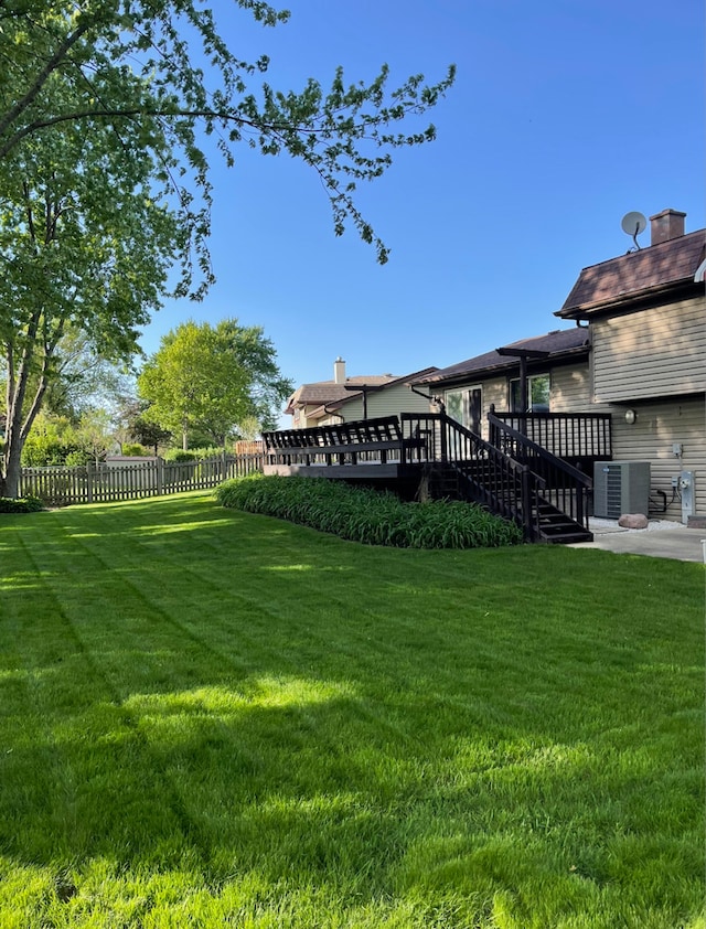 view of yard with a deck, stairs, fence, and central AC