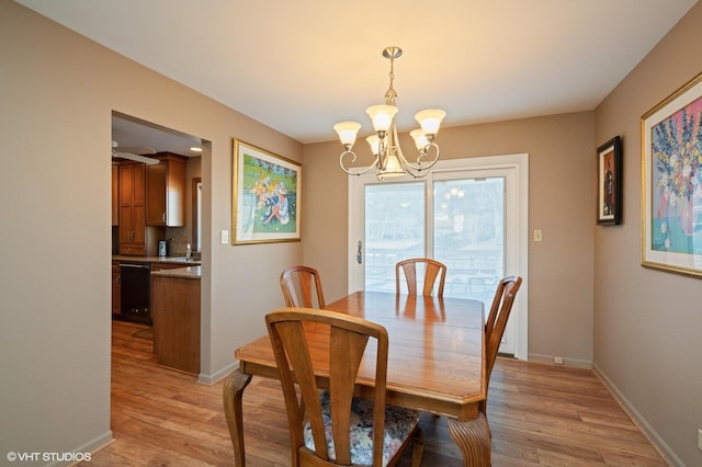 dining room featuring light wood finished floors, a notable chandelier, and baseboards