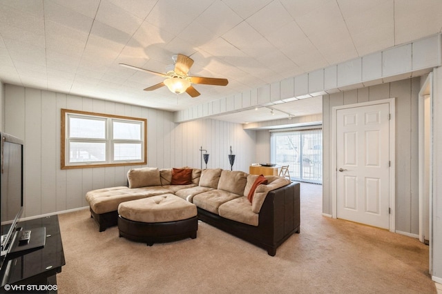 carpeted living area featuring a ceiling fan and baseboards