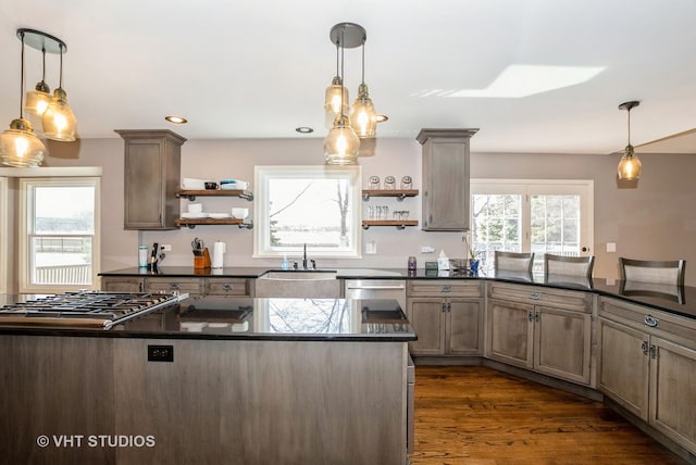 kitchen with dark countertops, a sink, stainless steel appliances, and open shelves