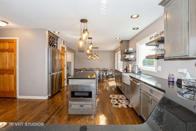 kitchen featuring dark wood finished floors, open shelves, a sink, stainless steel appliances, and decorative light fixtures