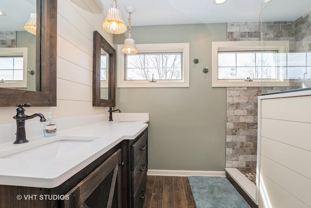 full bath featuring wood finished floors, a walk in shower, double vanity, and a sink