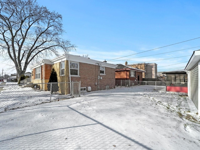 snow covered property with brick siding and a fenced front yard