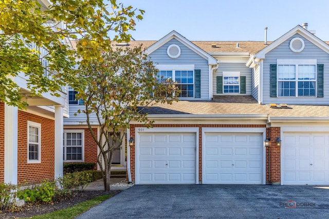 multi unit property featuring brick siding, a shingled roof, and aphalt driveway