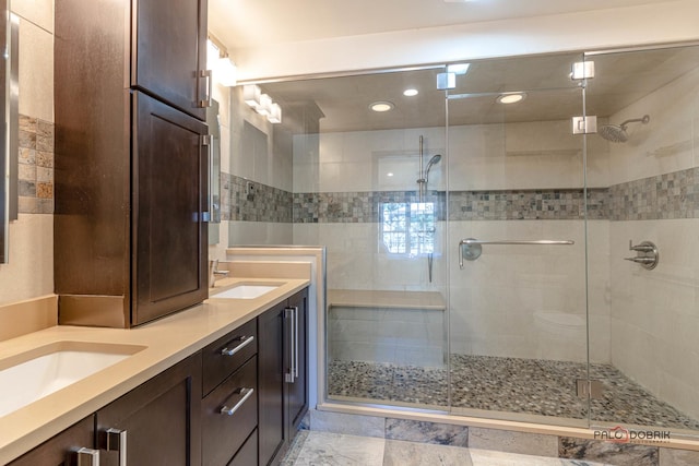 bathroom featuring double vanity, a shower stall, and a sink