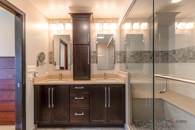 full bathroom with a sink, a stall shower, and double vanity