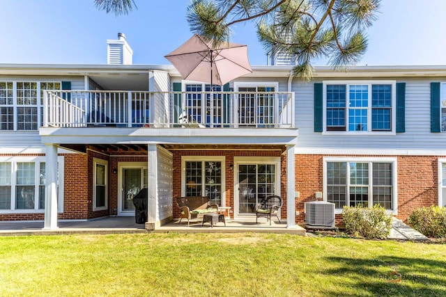 rear view of property with cooling unit, a patio, brick siding, and a yard