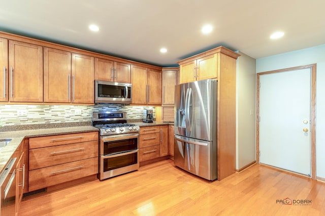 kitchen featuring tasteful backsplash, recessed lighting, stainless steel appliances, light wood finished floors, and light stone countertops