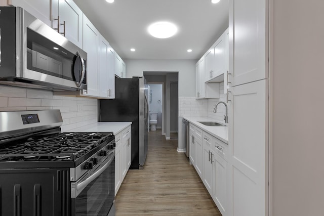 kitchen with appliances with stainless steel finishes, light countertops, light wood-style floors, and a sink