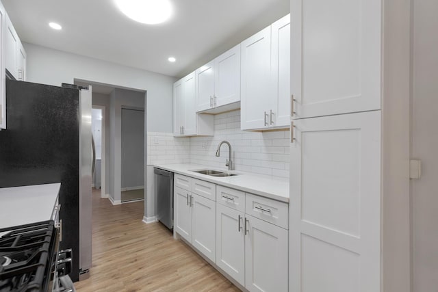 kitchen with light wood-type flooring, light countertops, decorative backsplash, appliances with stainless steel finishes, and a sink