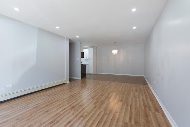 unfurnished room with a baseboard heating unit, baseboards, light wood-type flooring, recessed lighting, and a notable chandelier