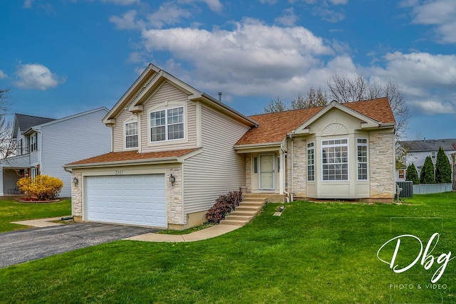 view of front of home featuring a front lawn, stone siding, a garage, aphalt driveway, and central air condition unit