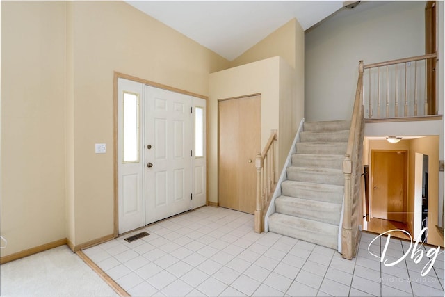 foyer entrance featuring stairway, light tile patterned floors, vaulted ceiling, and visible vents