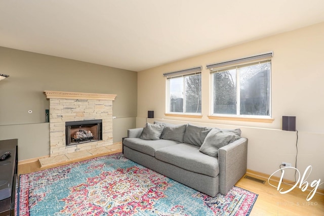 living room with a fireplace, wood finished floors, and visible vents