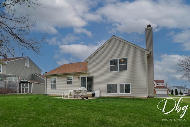 rear view of property featuring a shed, a chimney, a patio area, an outdoor structure, and a yard