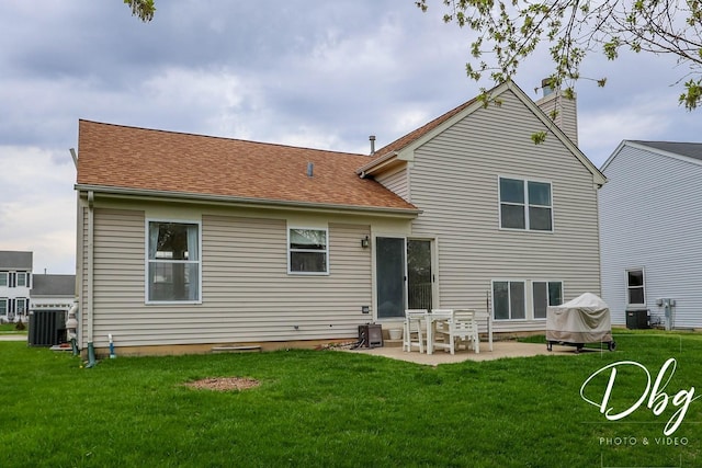 back of property with a patio, roof with shingles, a chimney, central AC unit, and a lawn